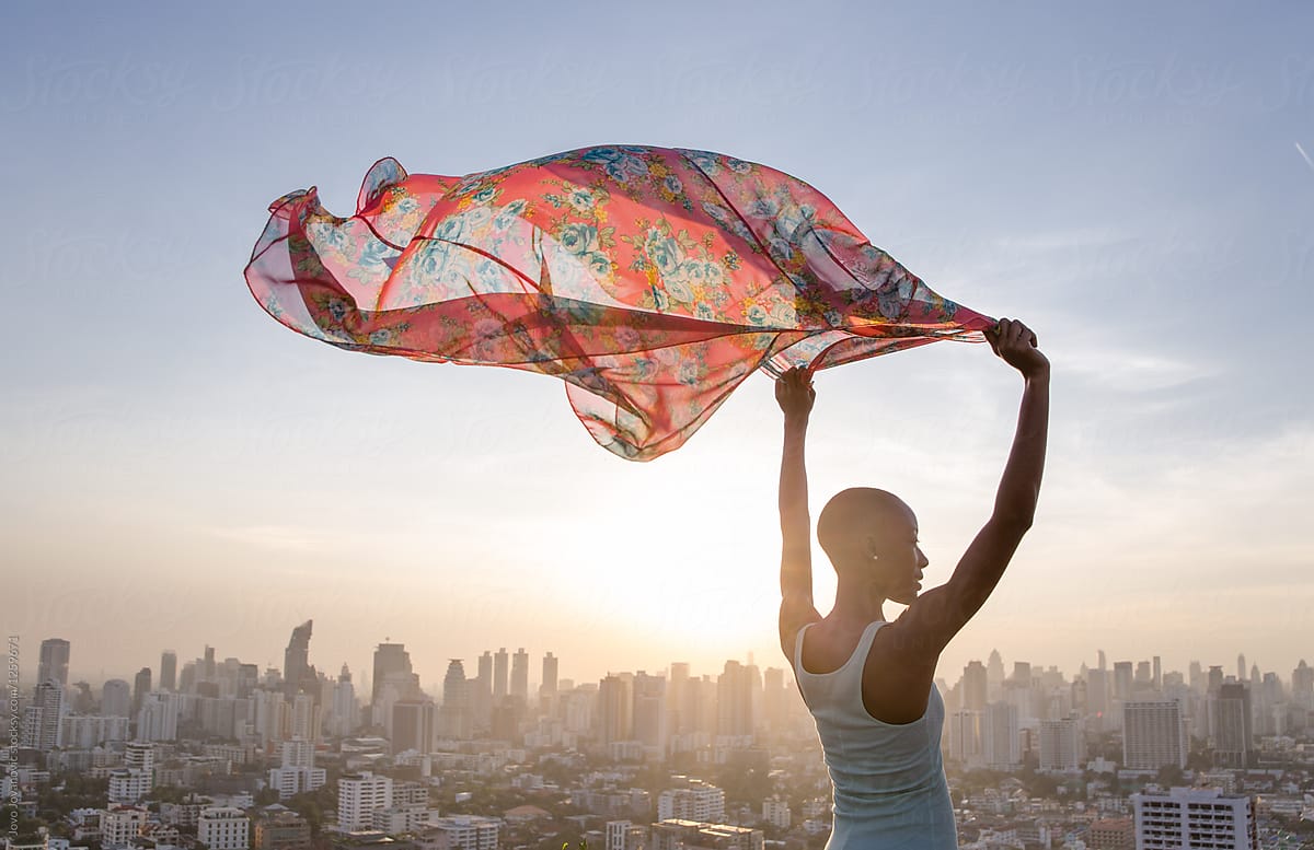 Woman holding up scarf to flatter in breeze in the city