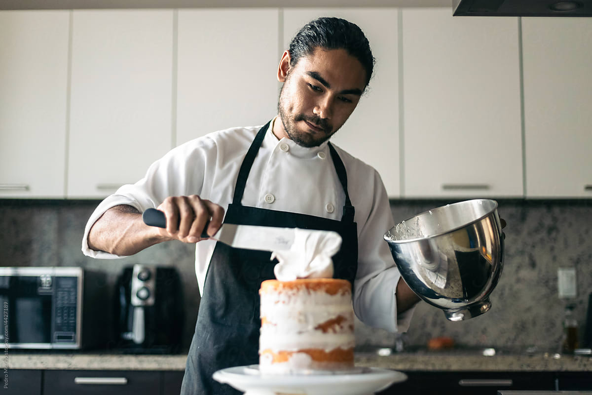 anonymous pastry chef pouring meringue on a cake