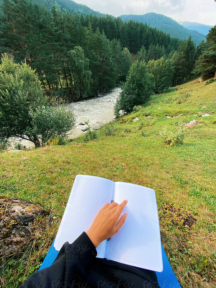 Crop woman reading book in mountains