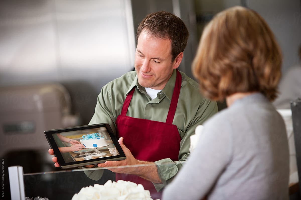 Bakery: Man Shows Cake Sample to Woman on Digital Tablet