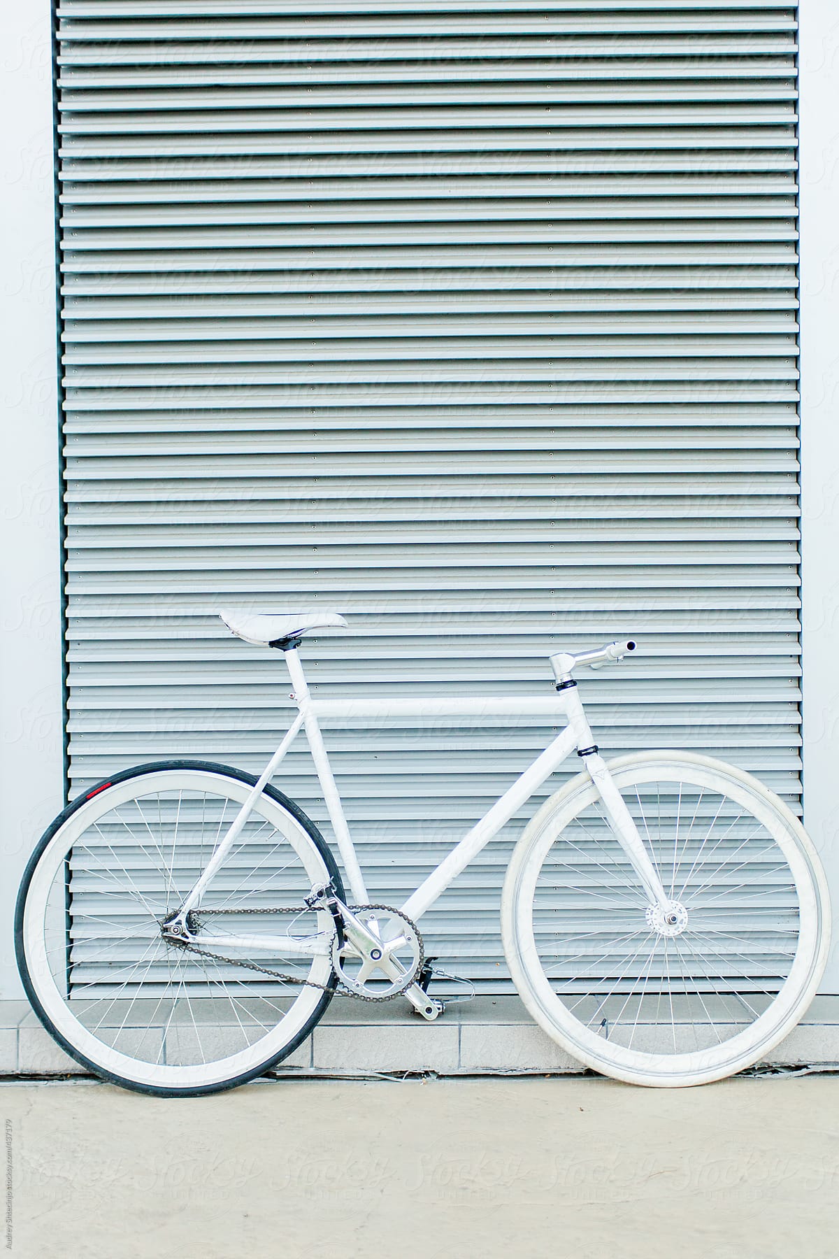 White fixie bike in front of minimalistic metal background,