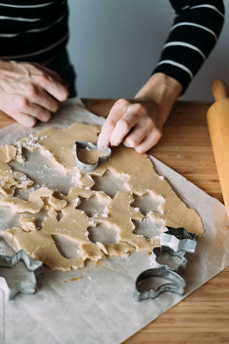 Woman cutting cookie dough with metal cutters.