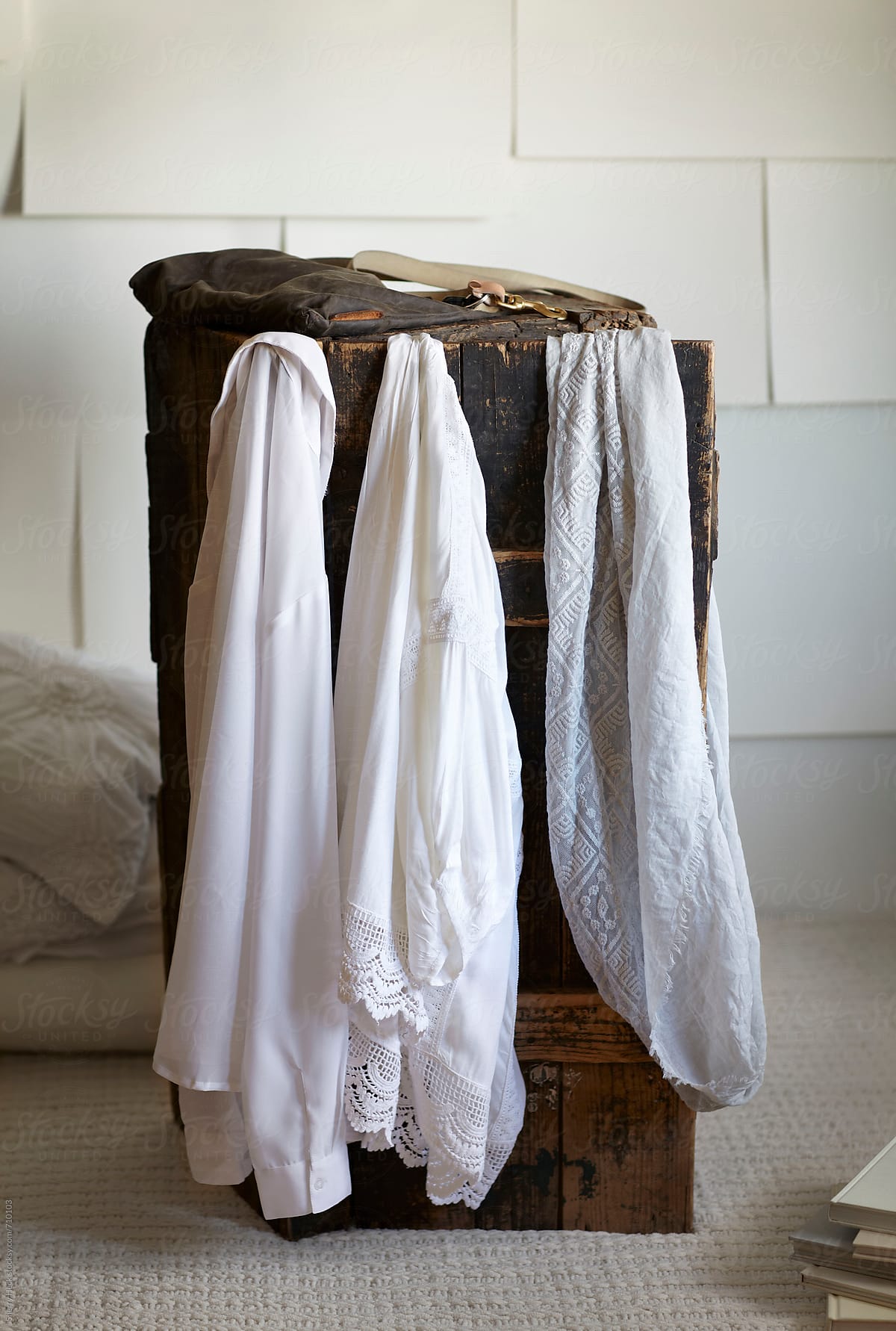 White hanging shirts on an old wood trunk in white paper room