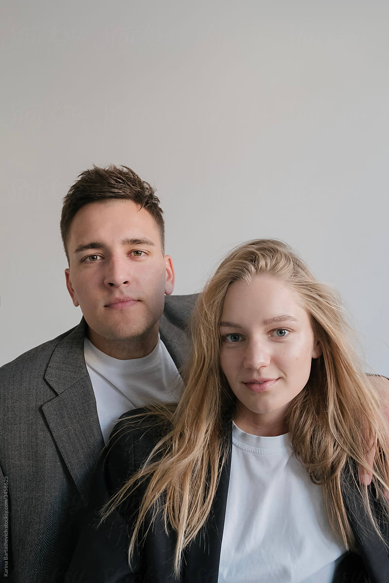 portrait of brother and sister, brother put his hand on his sister's shoulder in a light studio