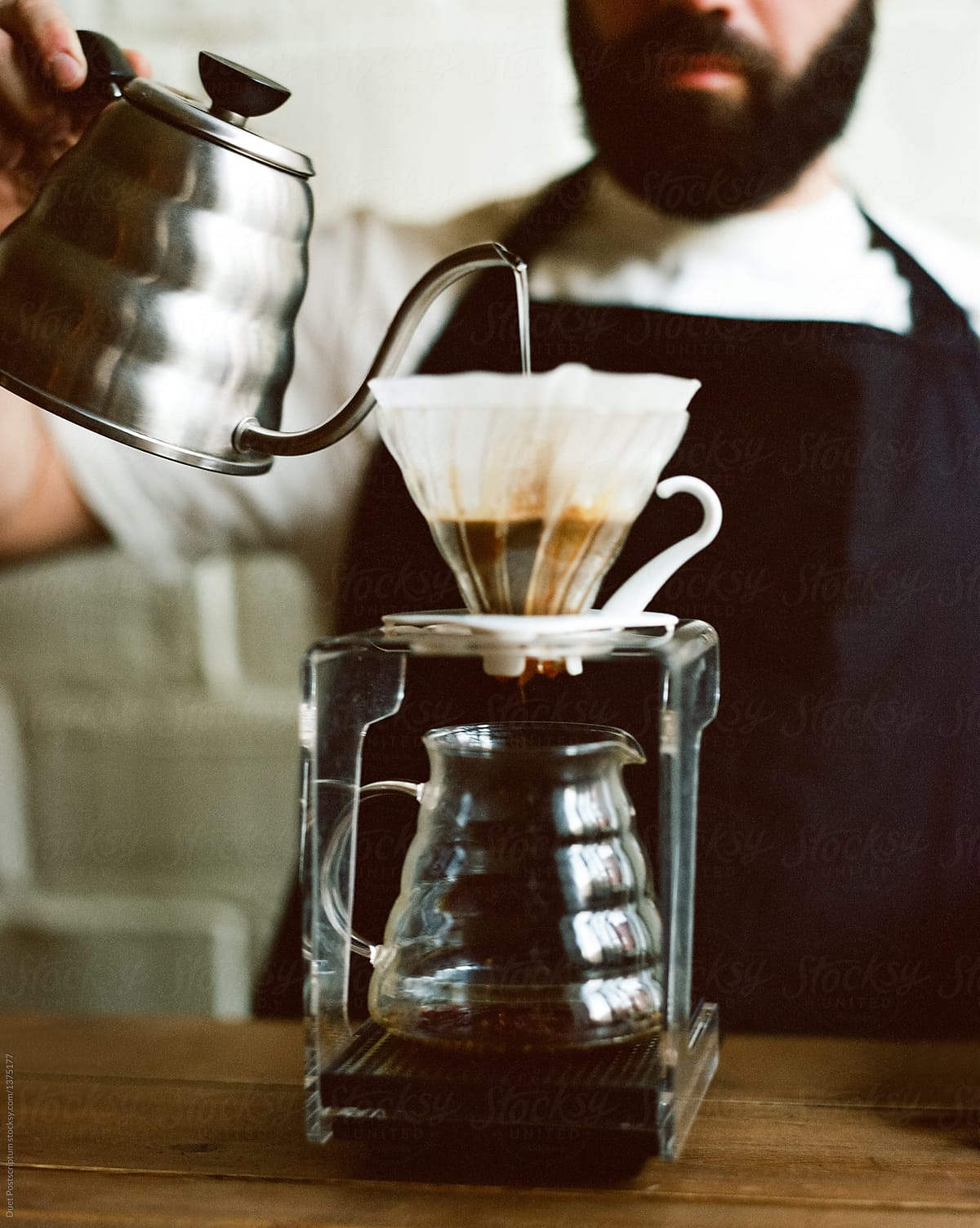 Faceless barista pouring hot water in chemex