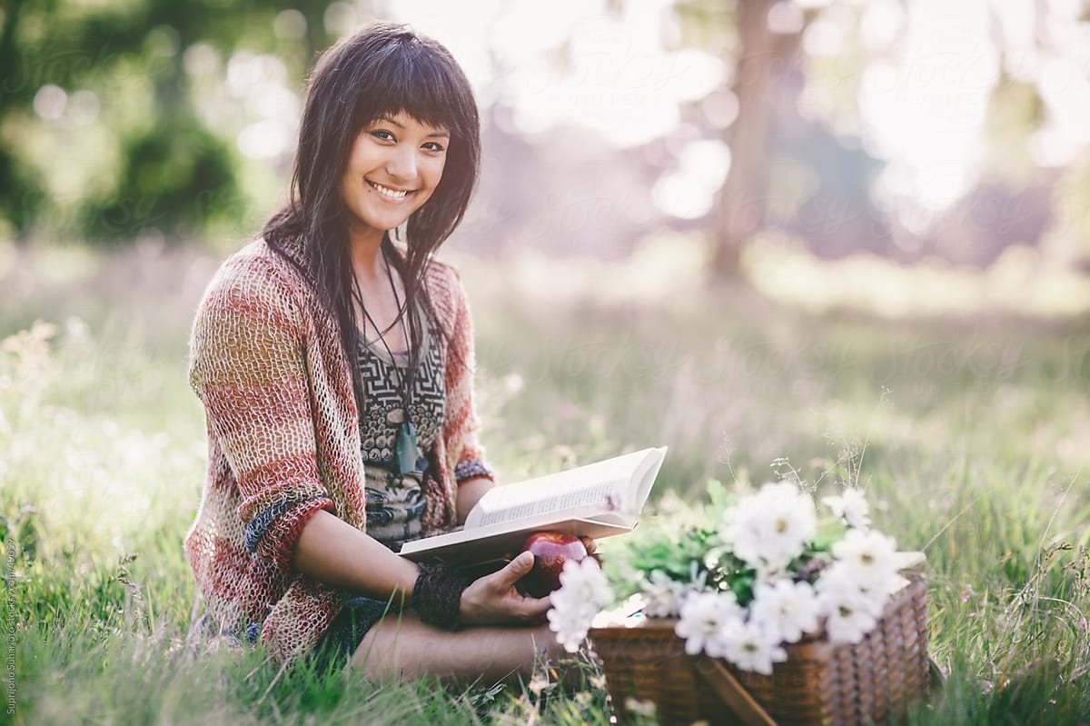 Beautiful woman reading a book on a grass field