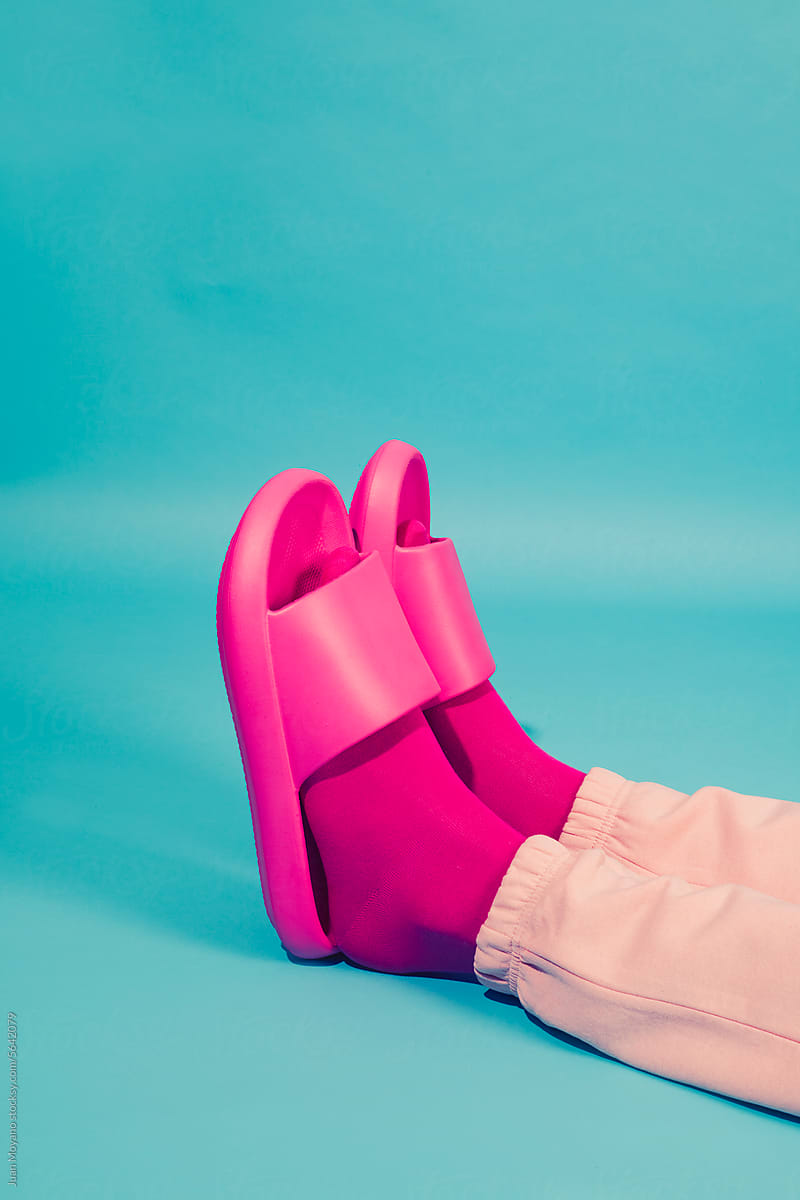 man laying on a blue background wearing pink socks and sandals