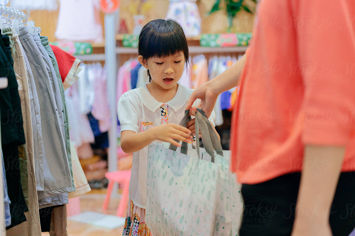 Little girl holding shopping bags in clothing store