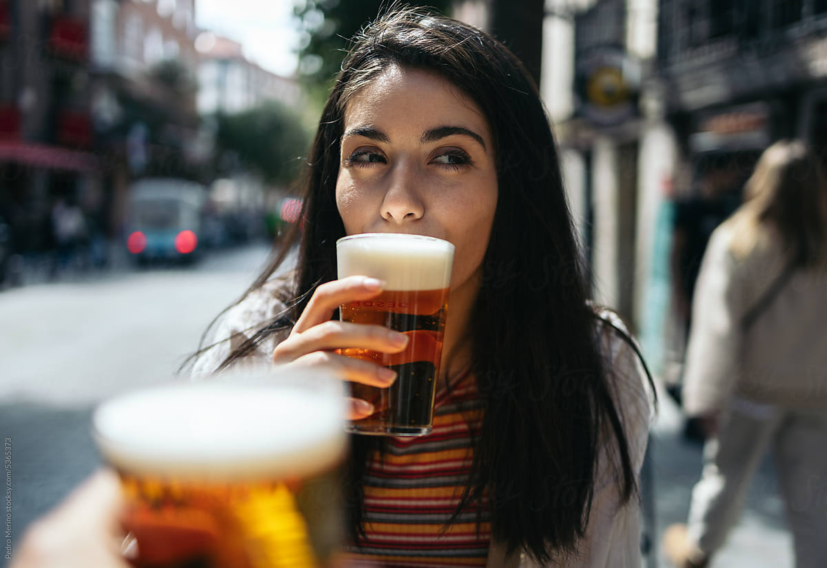 woman drinking beer in an outdoor terrace in the city street