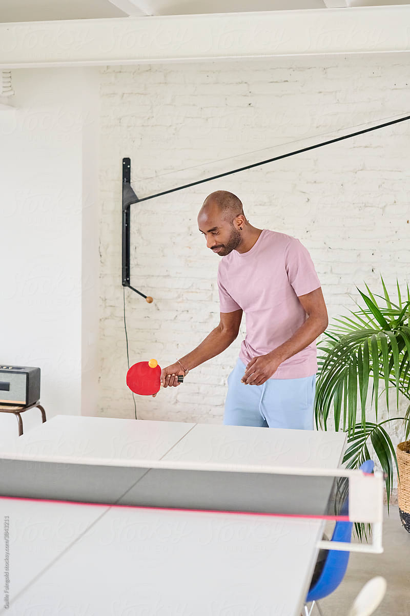 Black guy playing table tennis at home