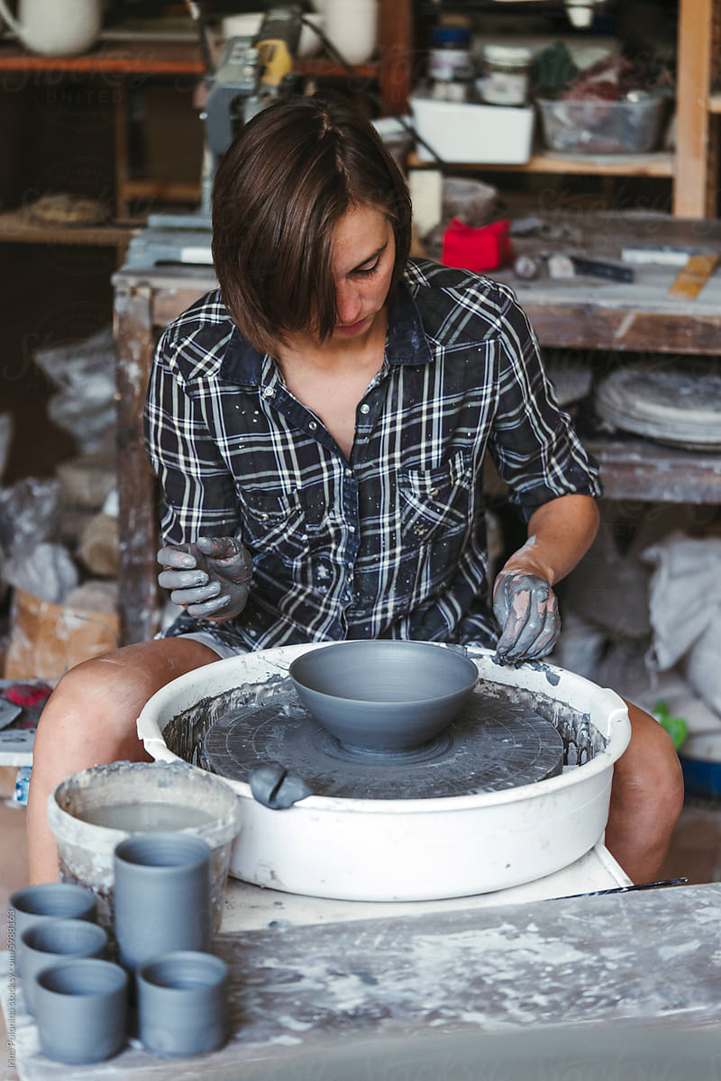 Modern Woman Potter Shaping Clay on Wheel in Studio