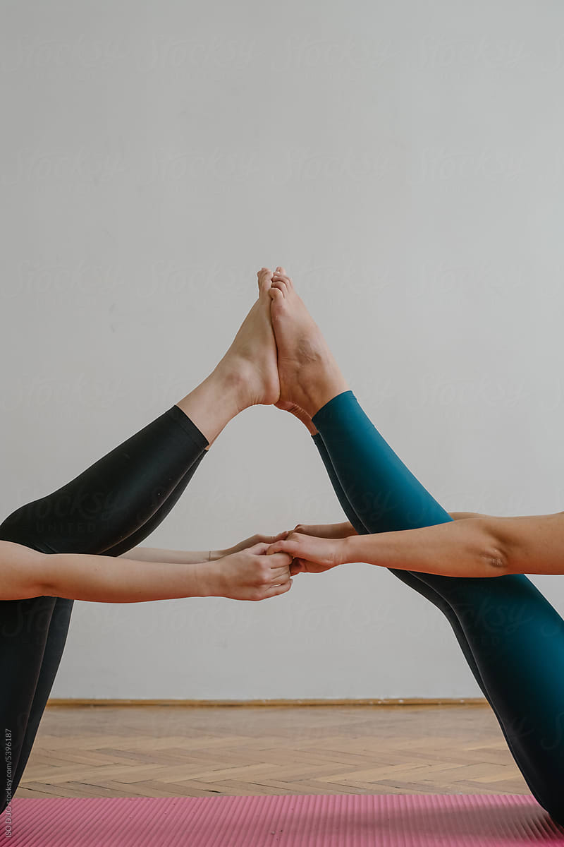 Two Women Standing In Warrior Pose On Yoga Mats by Stocksy