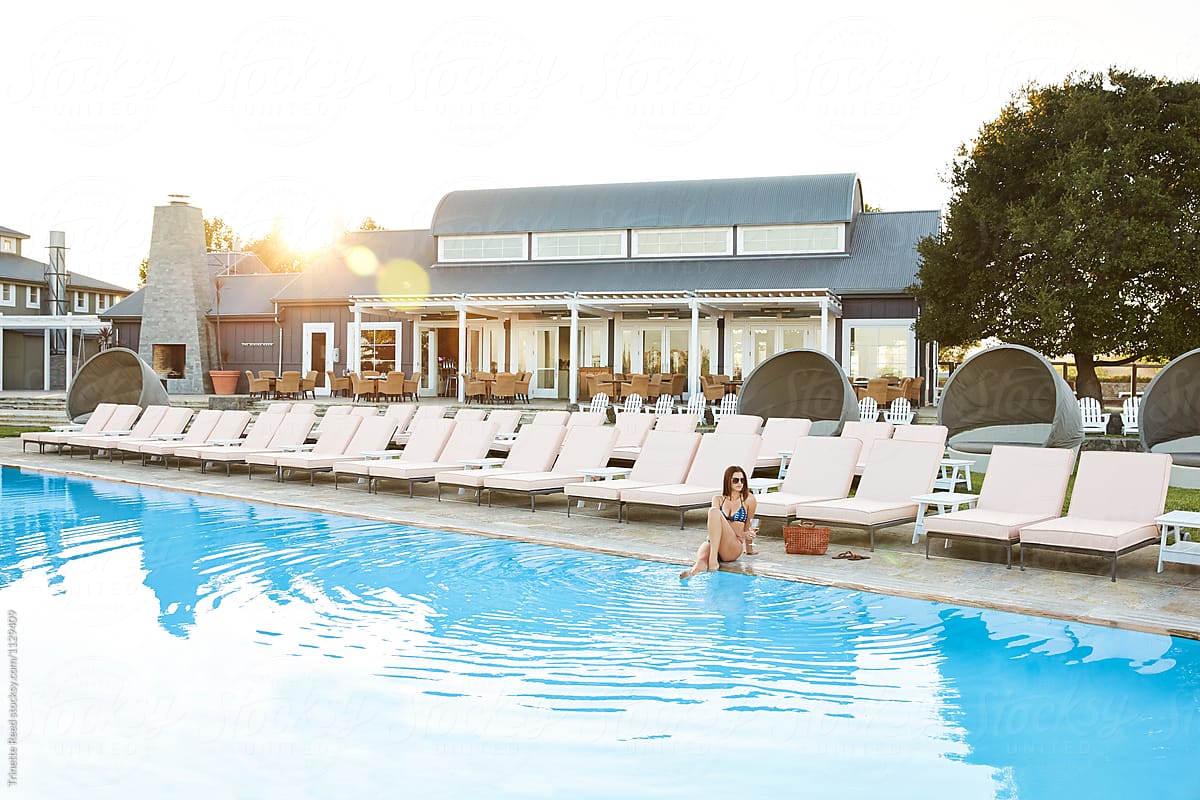 Woman lounging by pool at luxury resort at sunset
