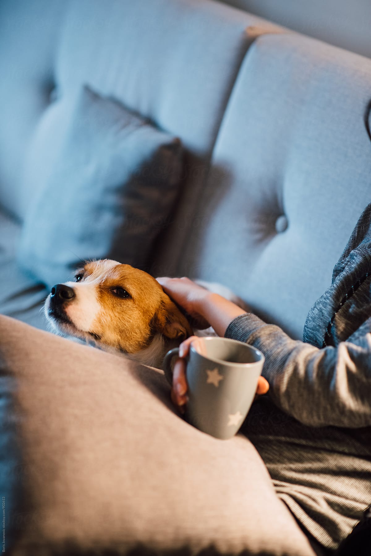 Woman cuddling a dog and drinking tea