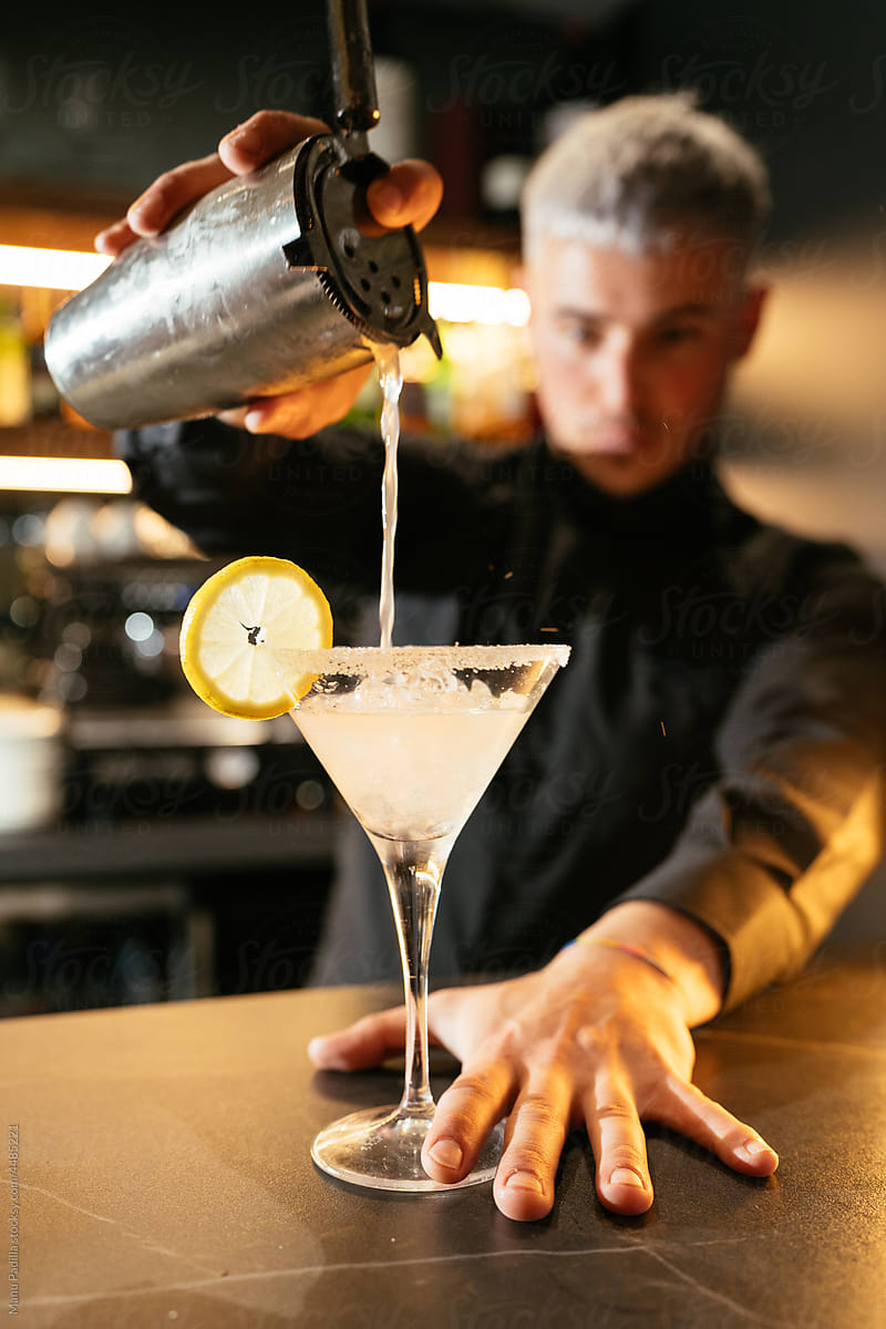 Bartender pouring cocktail into glass with ice