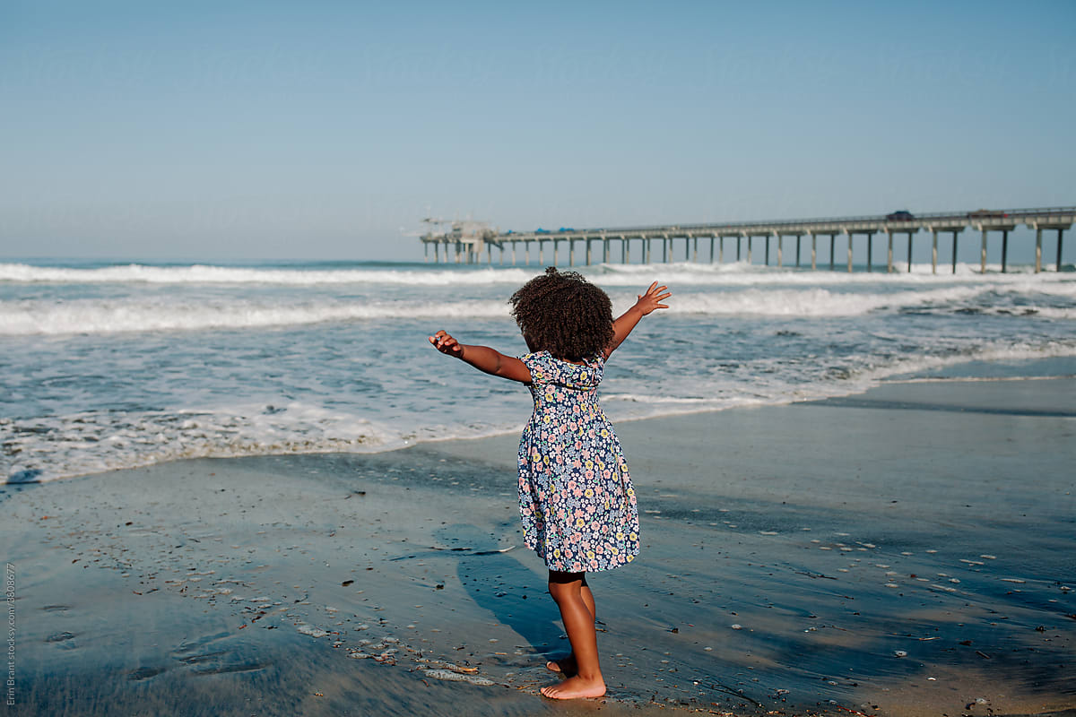 Young girl on beach with outstretched arms