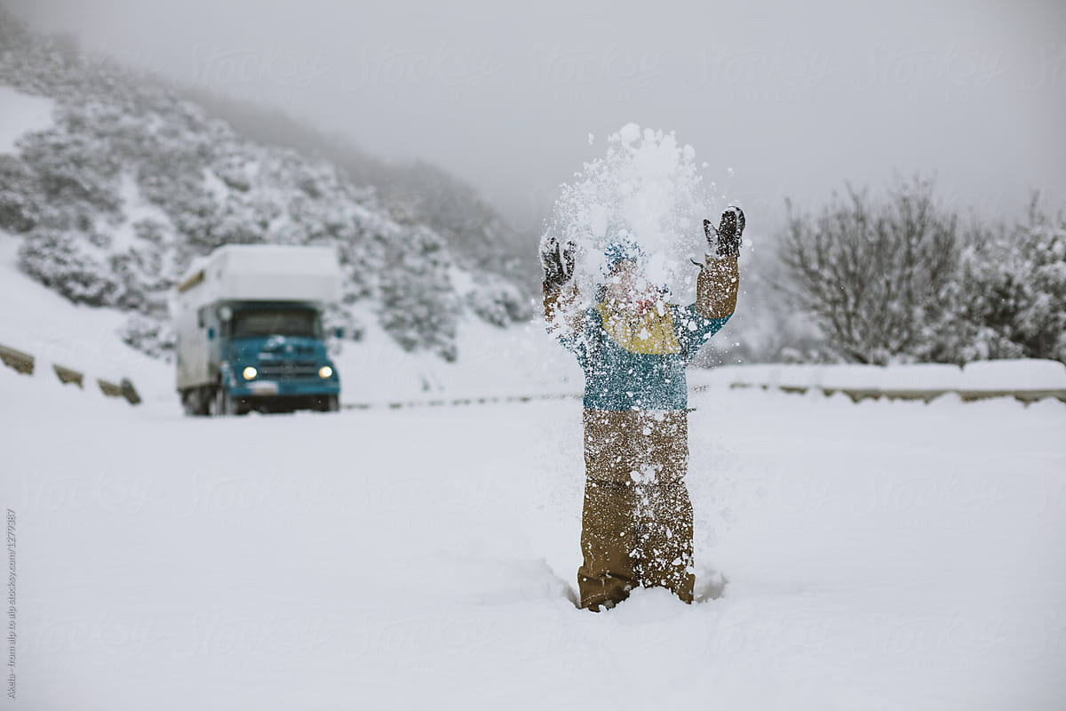 cute toddler having fun in the snow with a truck in the back
