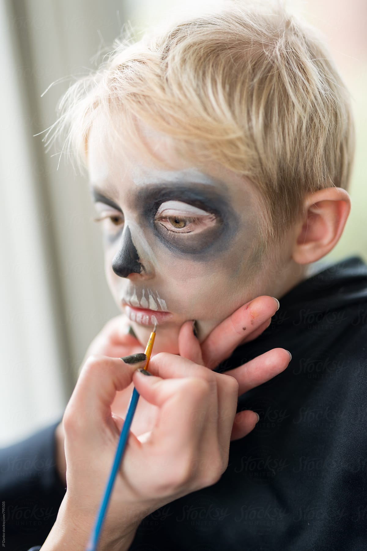 Mother Applying Halloween Costume Make Up for Blonde Boy