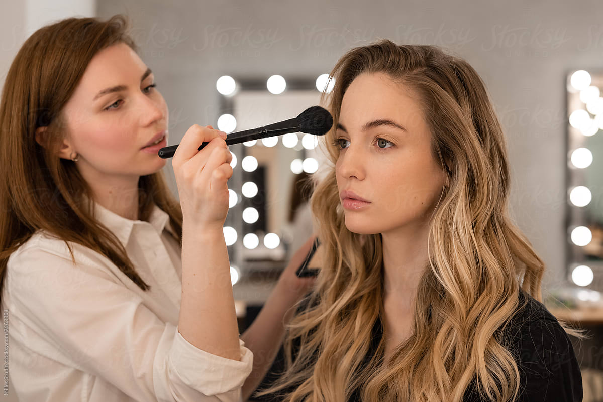 Makeup artist applying bronzer on model face