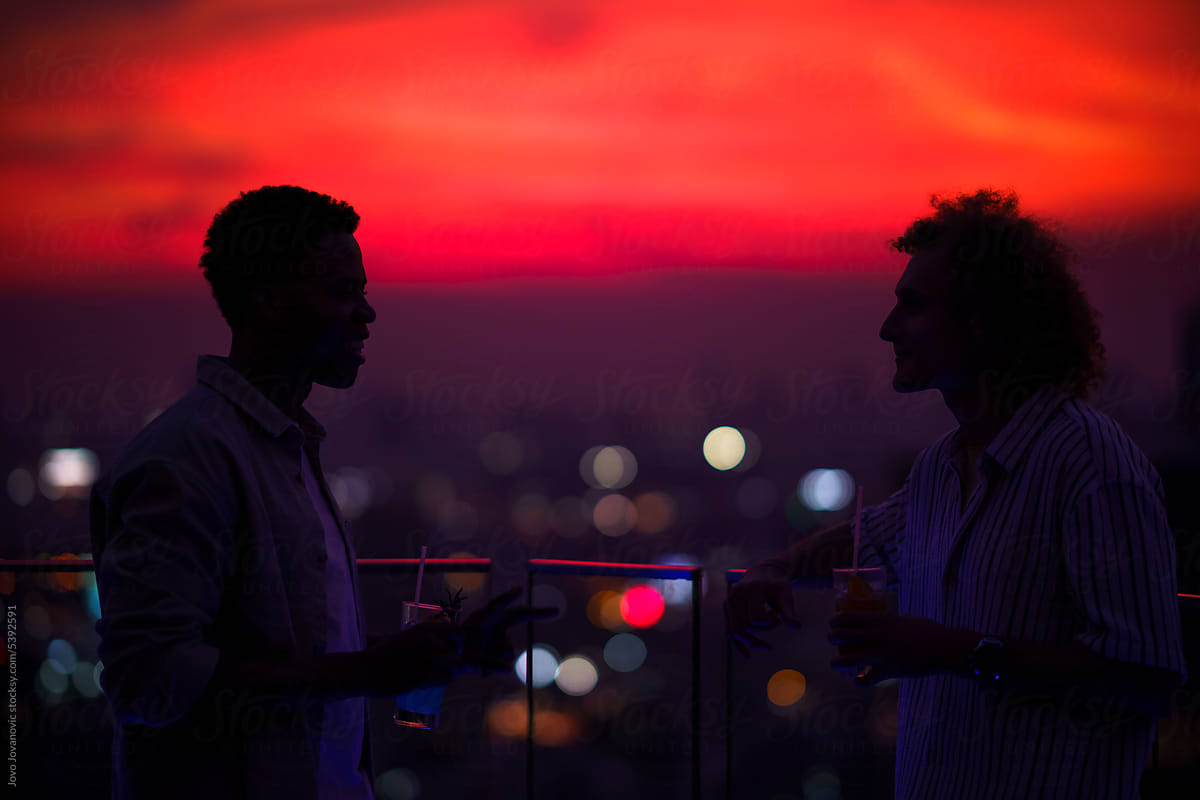 Friends talking during sunset drinks on rooftop
