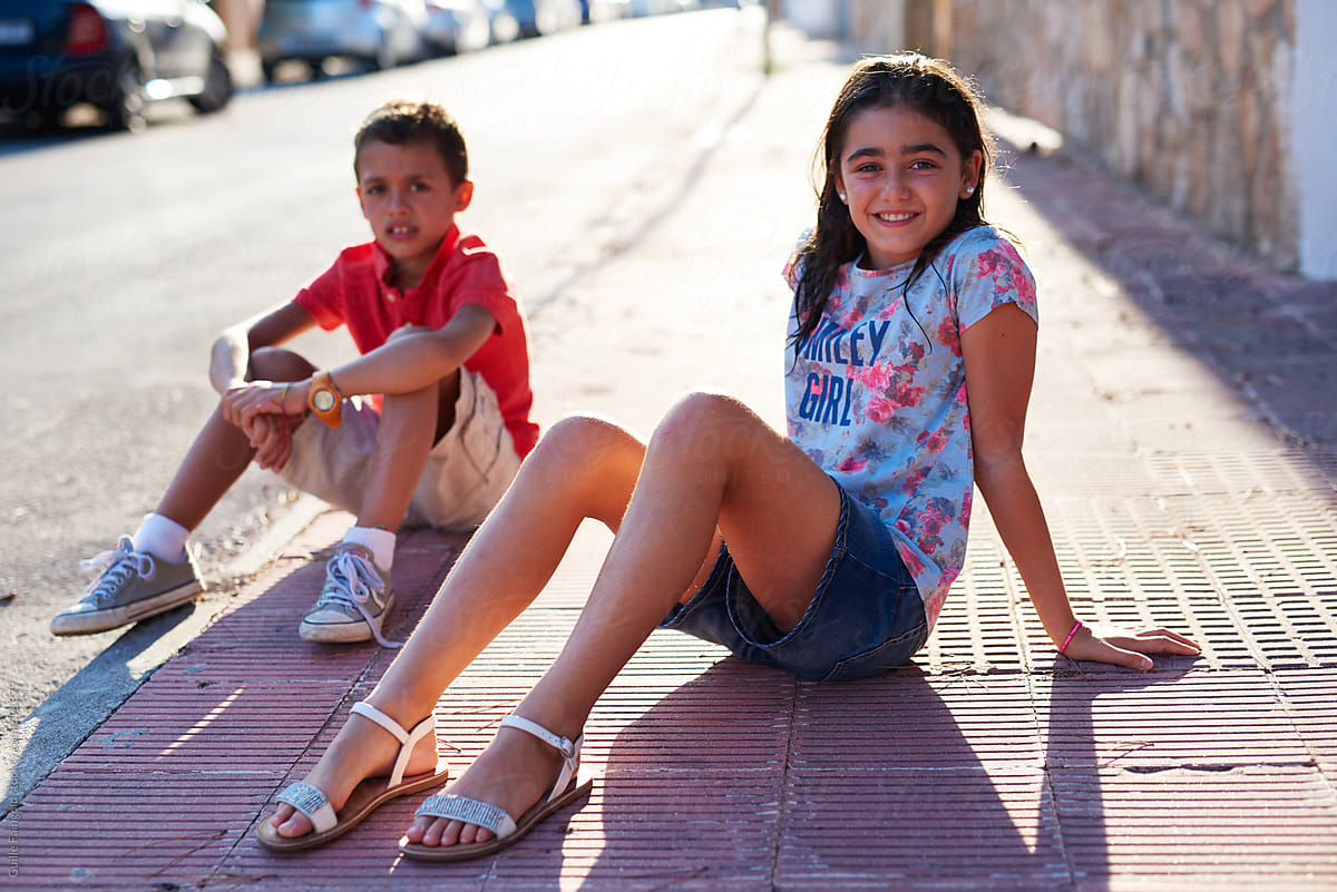 Sister And Brother Resting On Sidewalk By Stocksy Contributor Guille