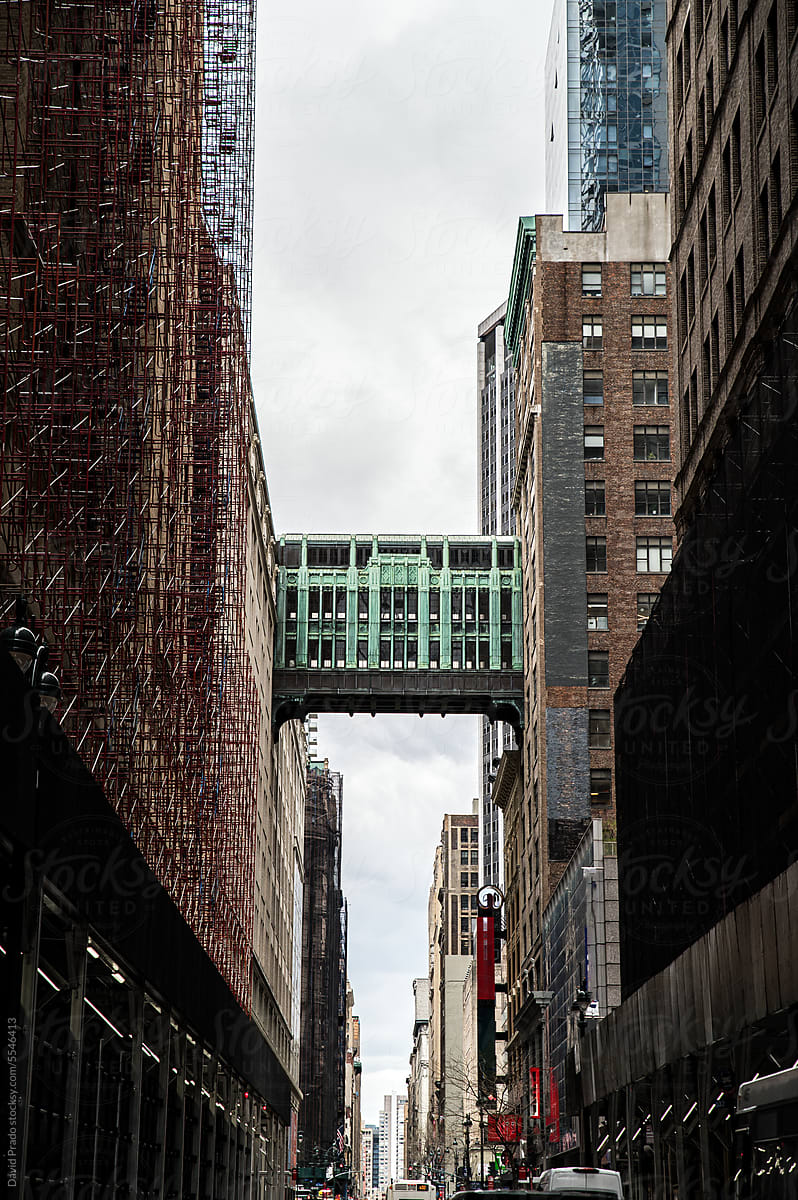 Green skywalk bridge suspended between two skyscrapers