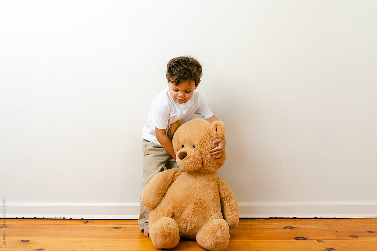 little boy playing with big teddy bear