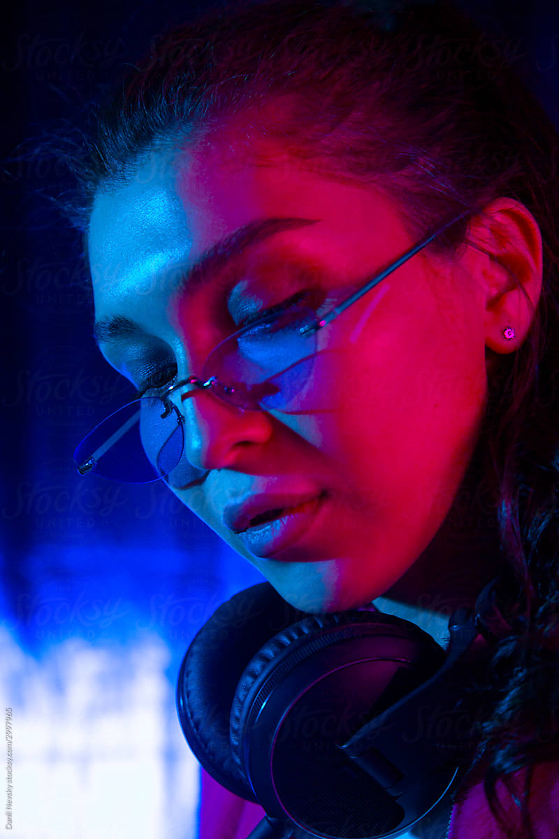 Modern woman with headphones standing in neon light