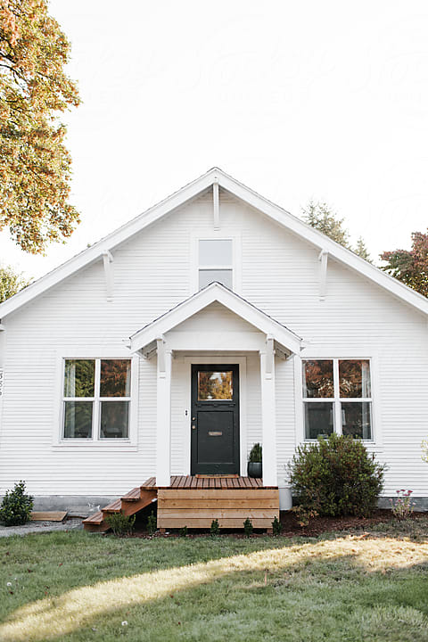 Simple two-story white house with wooden door, windows, and porch