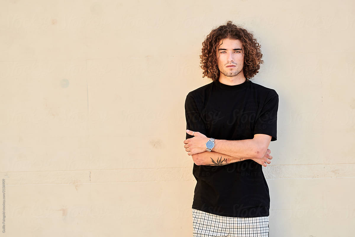Self-confident man with curly hair with folded arms.