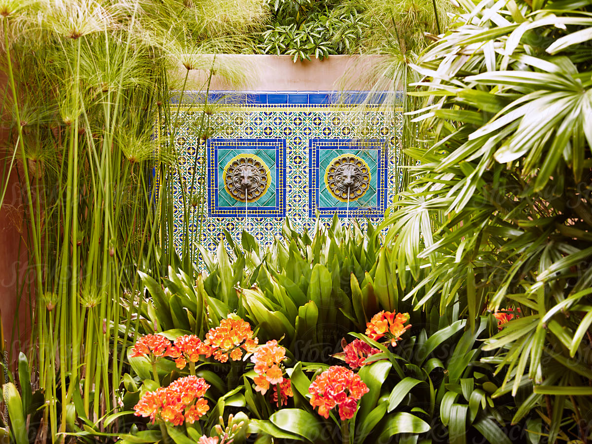 Tiled water fountain with lush tropical plants at spa.