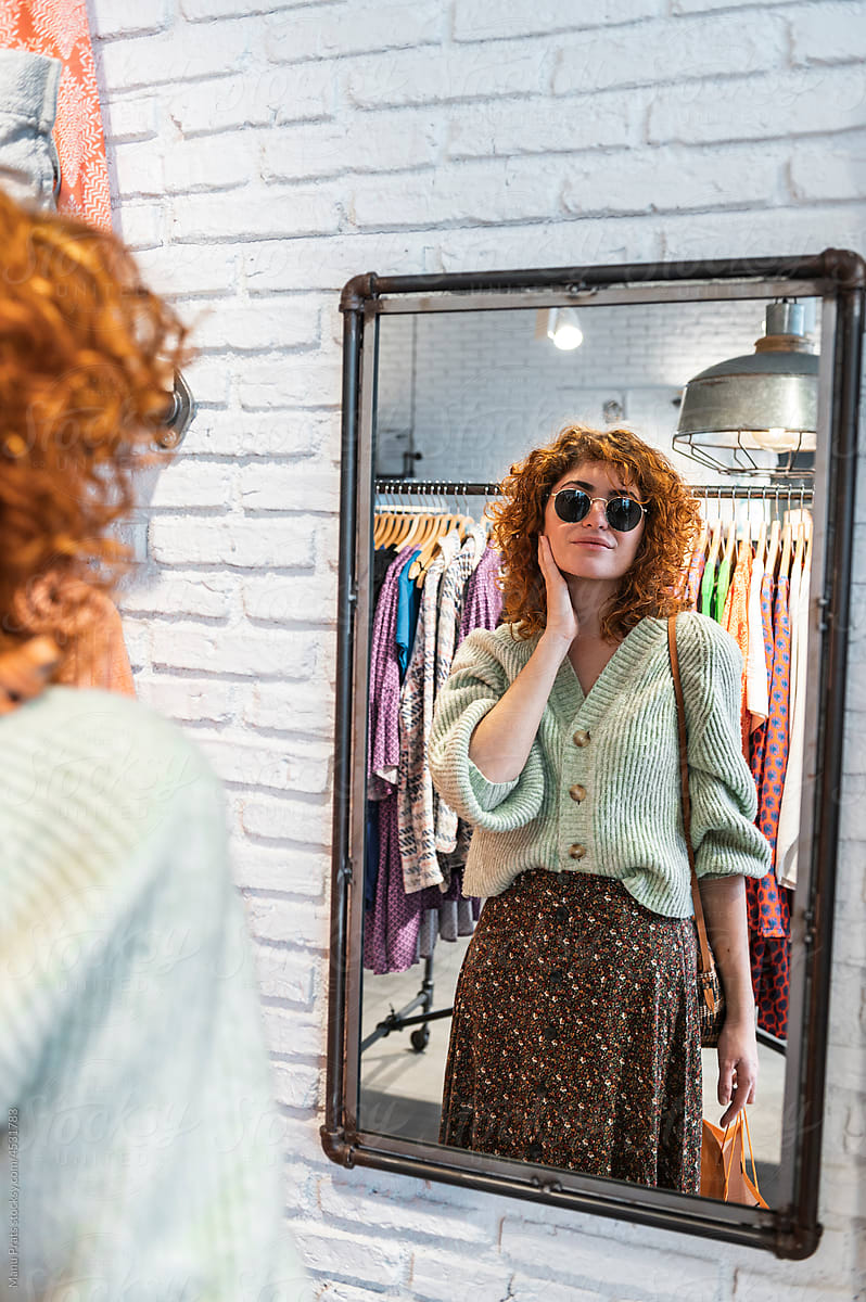 Redhead woman trying on sunglasses in shop
