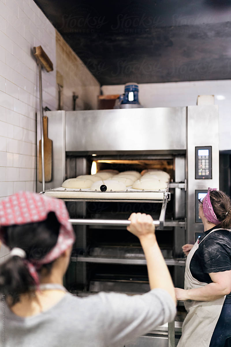 Woman taking out pastry from the oven.