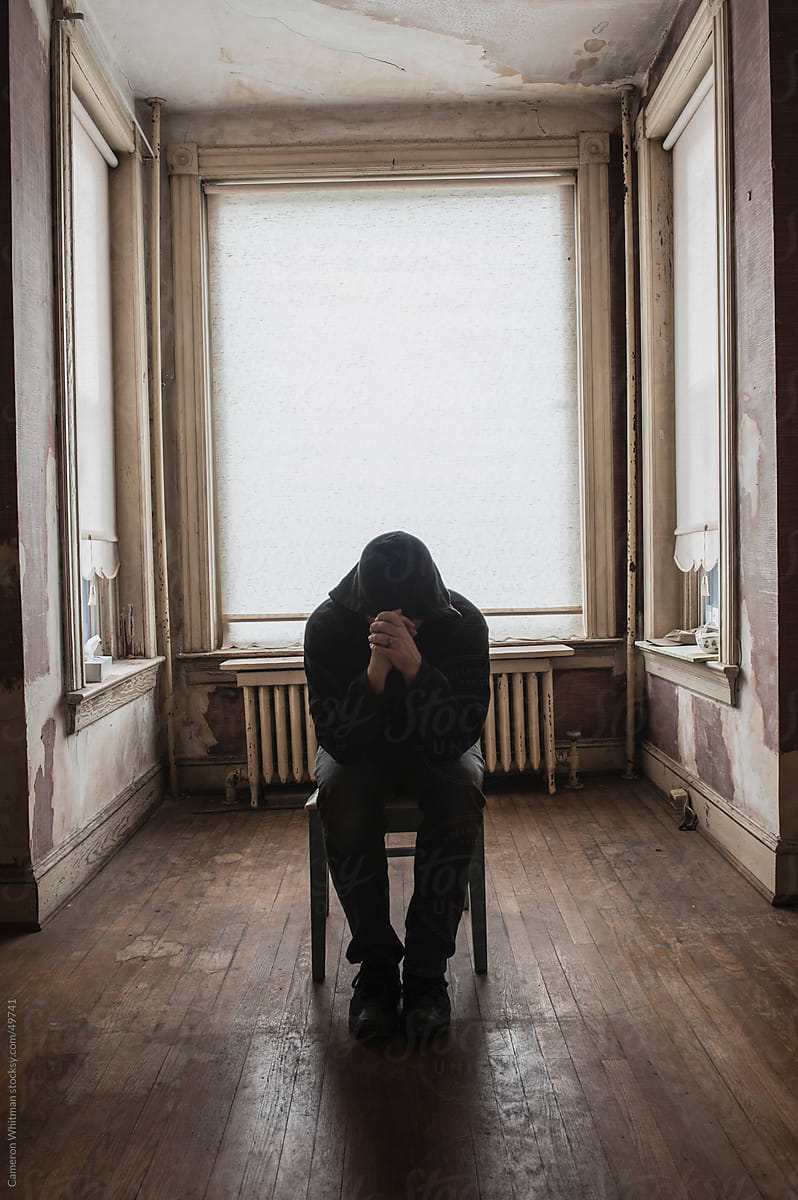 Lonely man praying in an abandoned room.