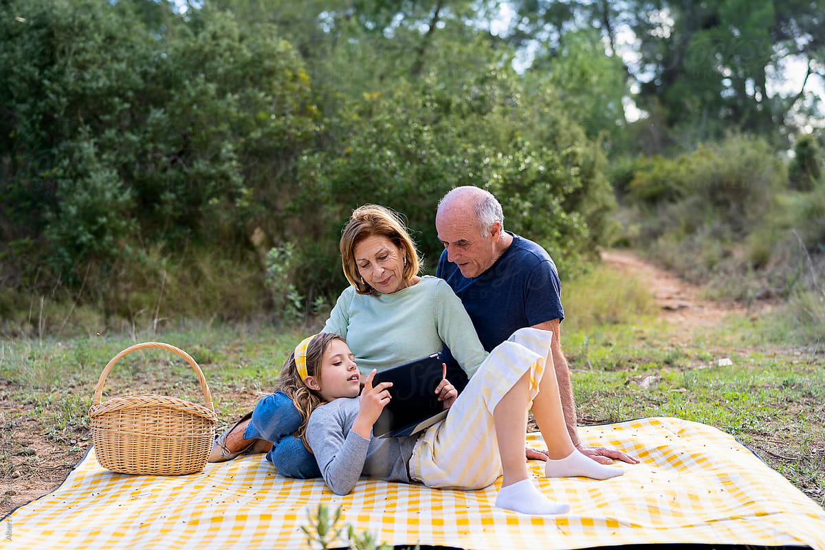 Smiling grandparents watching tablet with girl in woods