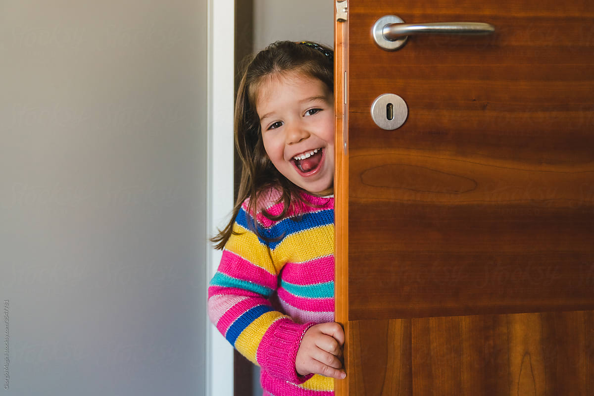 Playful Preschooler Girl Hiding Behind a Door