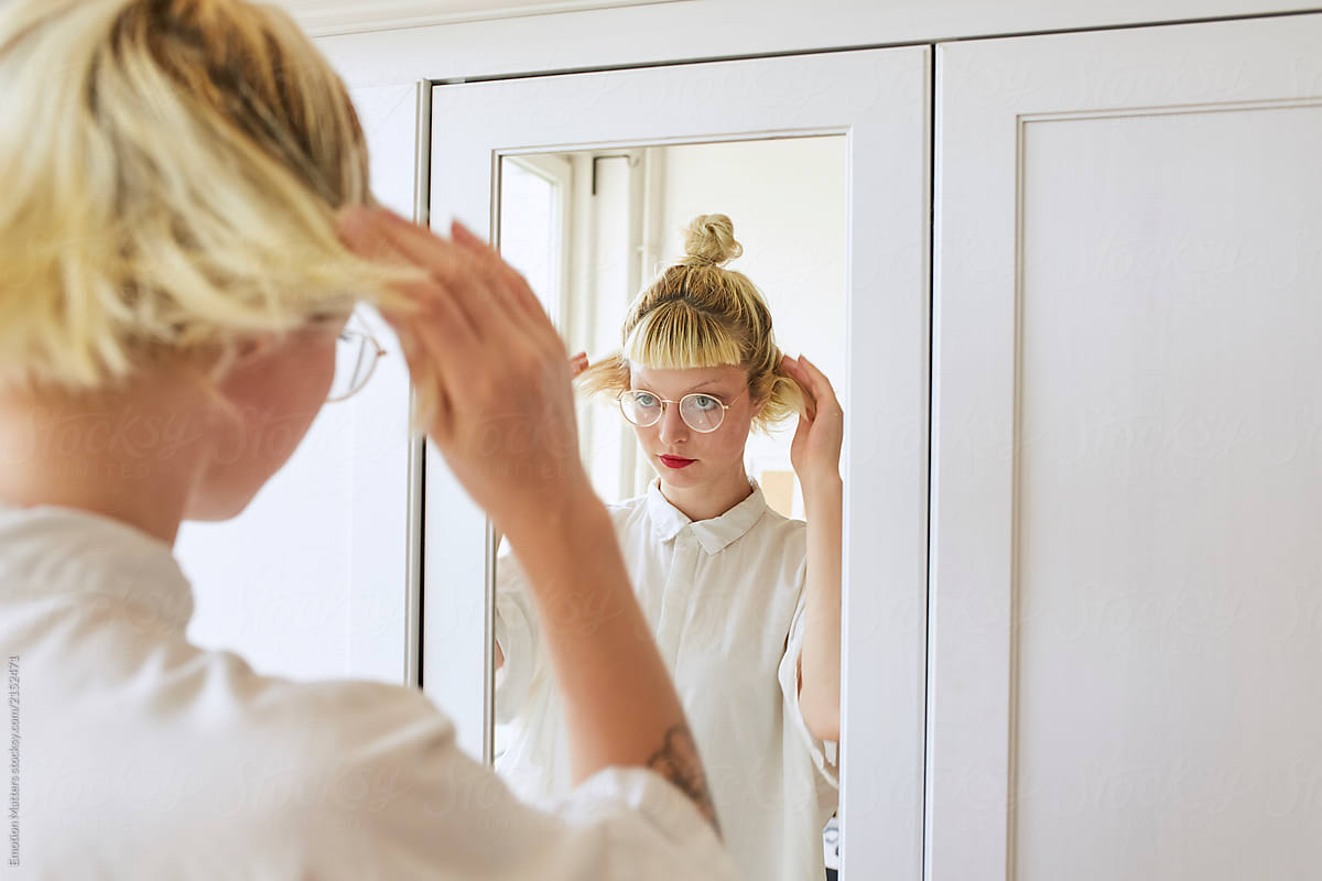 Woman fixing her hair in front of the mirror
