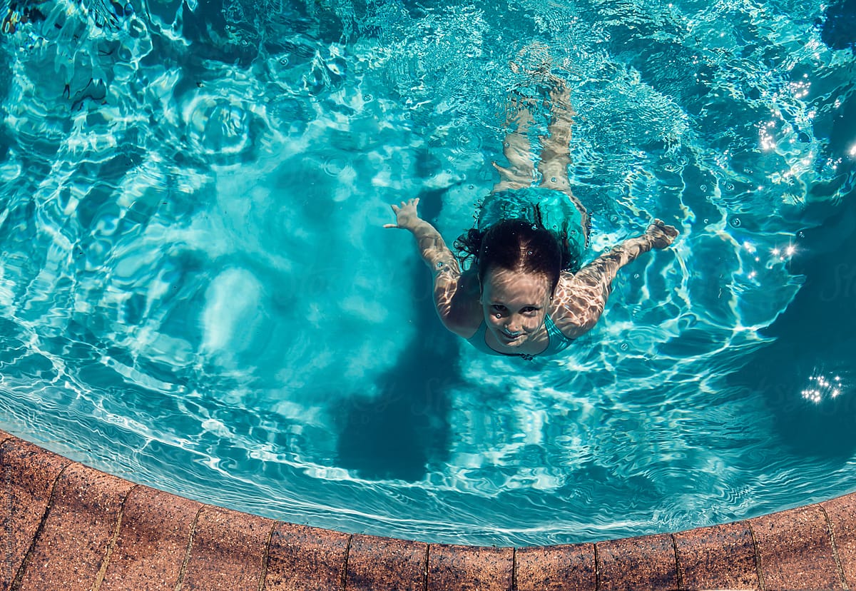Girl Surfacing In Swimming Pool View From Overhead By Stocksy