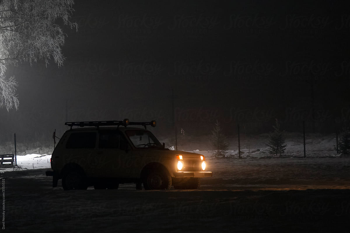 Car with glowing headlights in night countryside