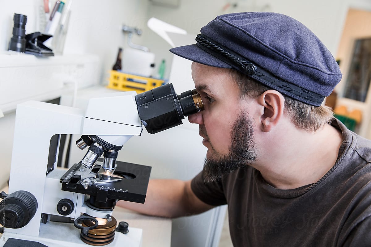 Young brewmaster looking through a microscope in a lab