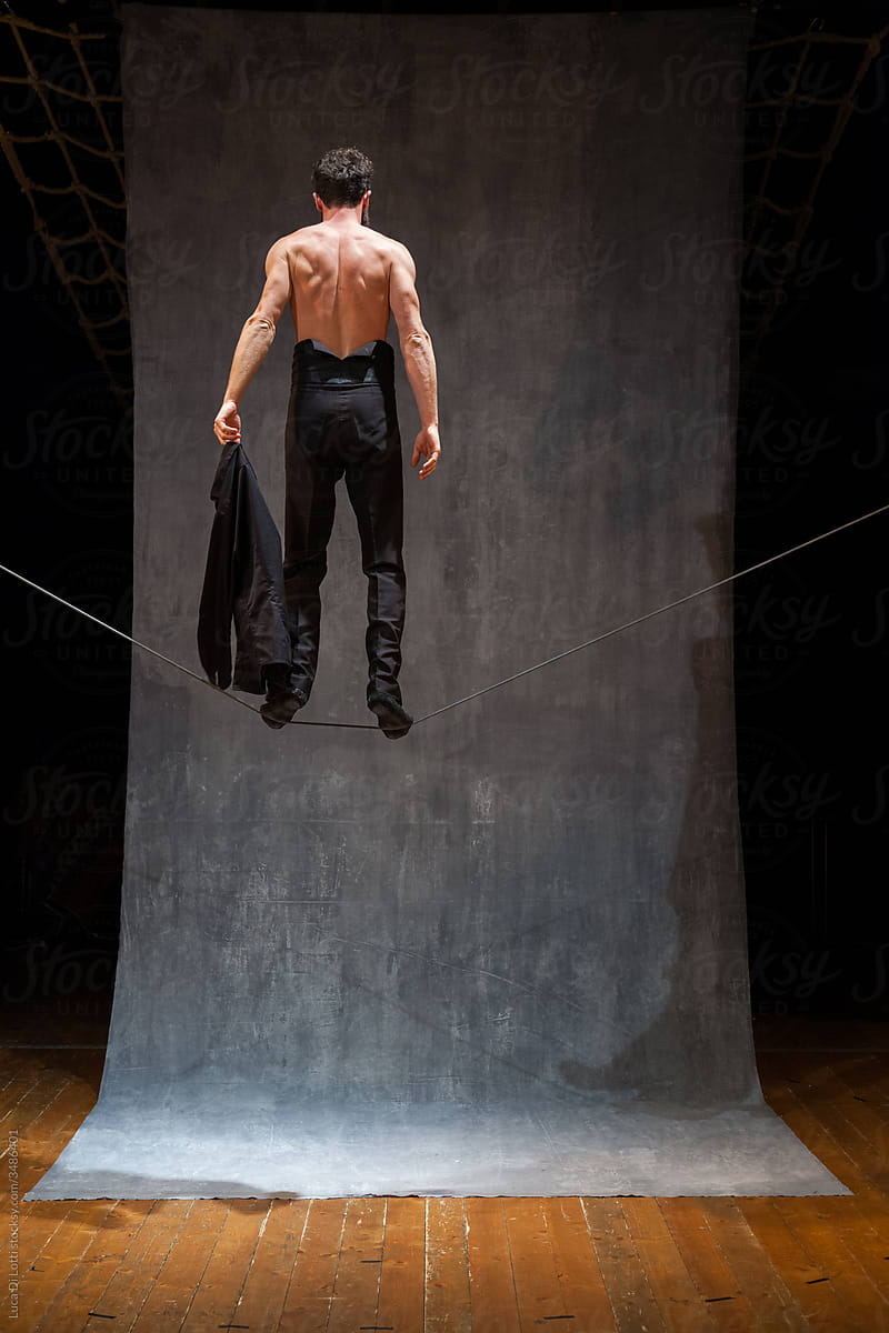 shirtless man standing on a wire