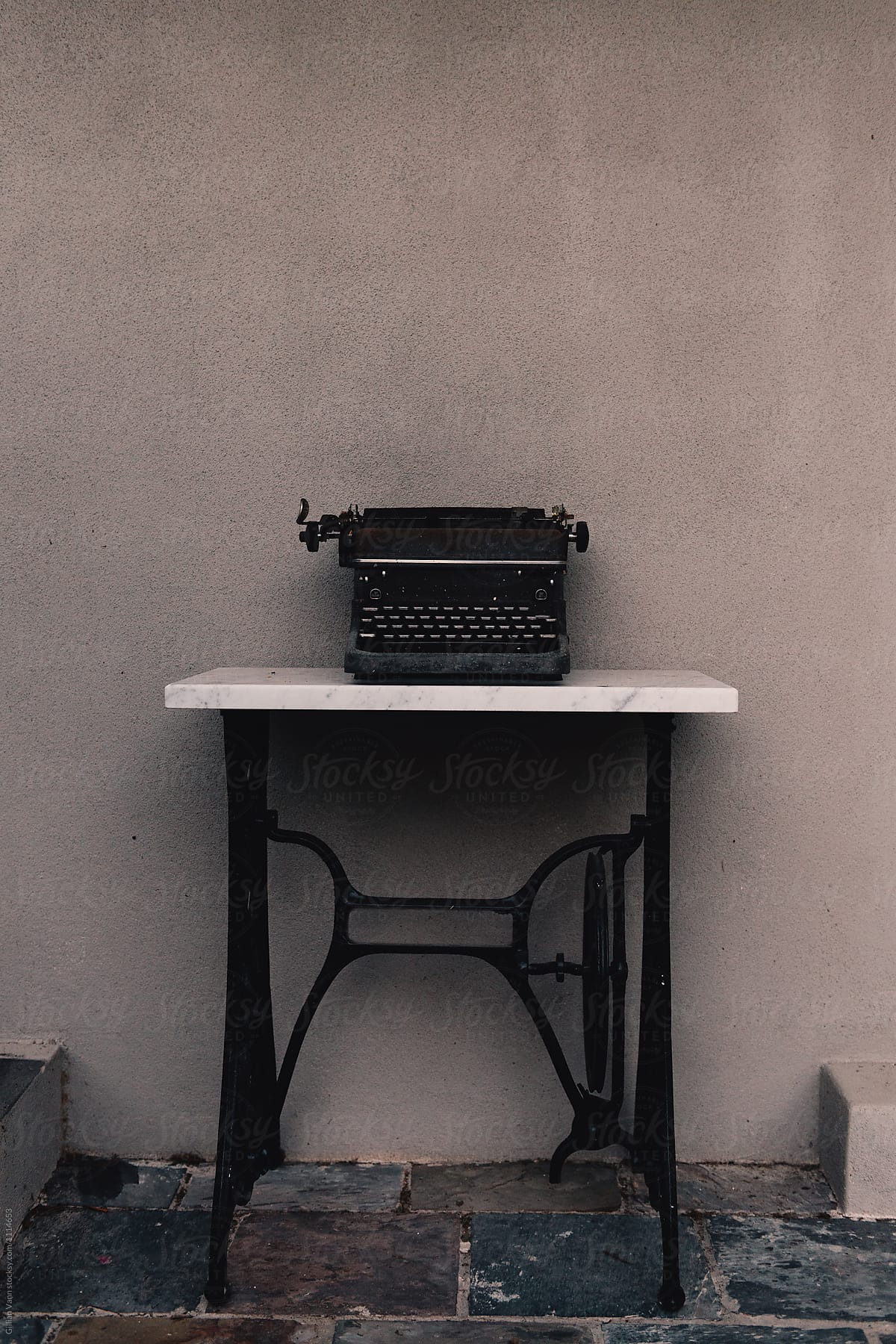 old vintage typewriter outdoors against a grey wall on a repurposed sewing machine table