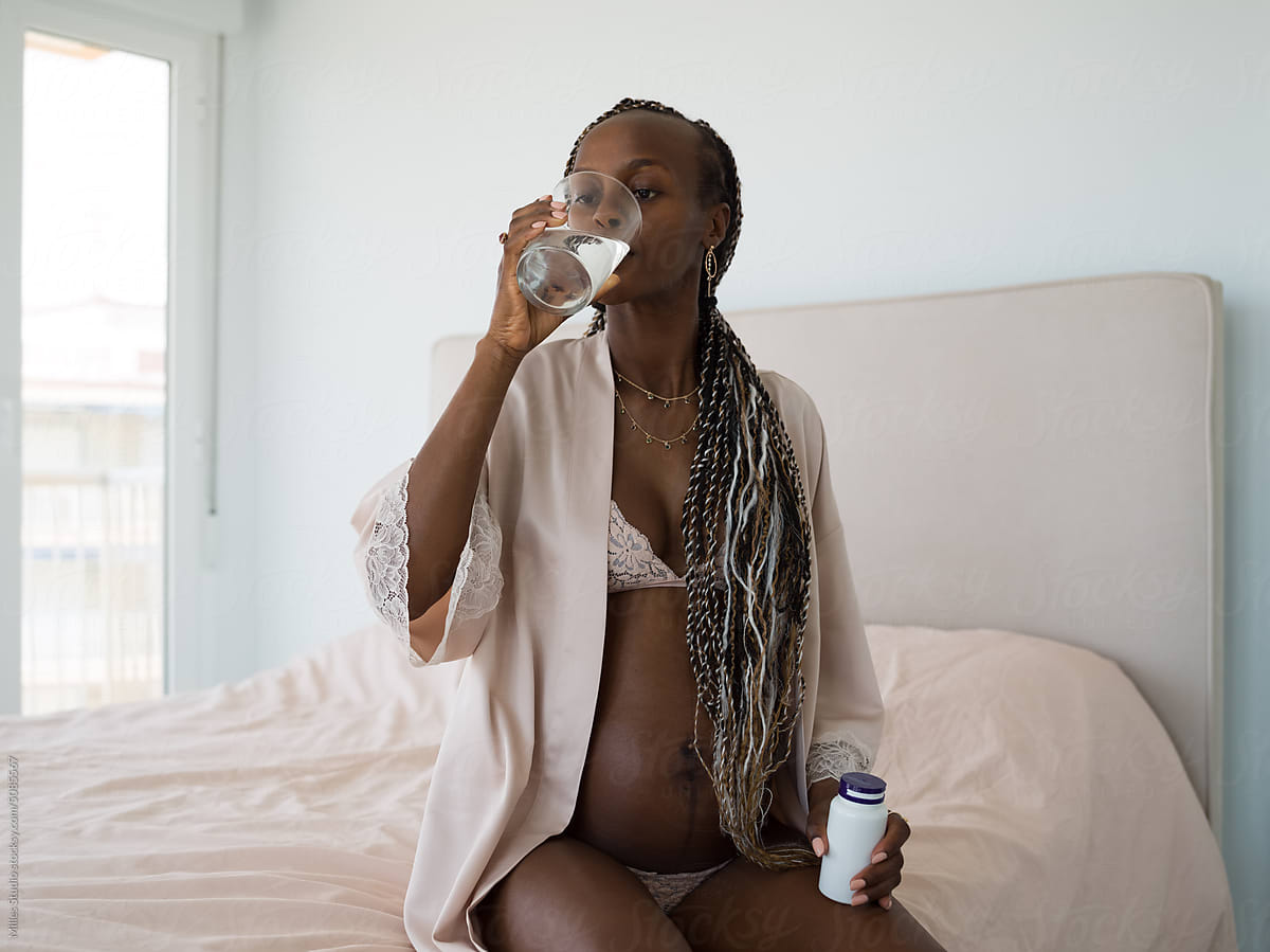 Black Woman Expecting Baby Taking Vitamins by Stocksy Contributor Milles  Studio - Stocksy