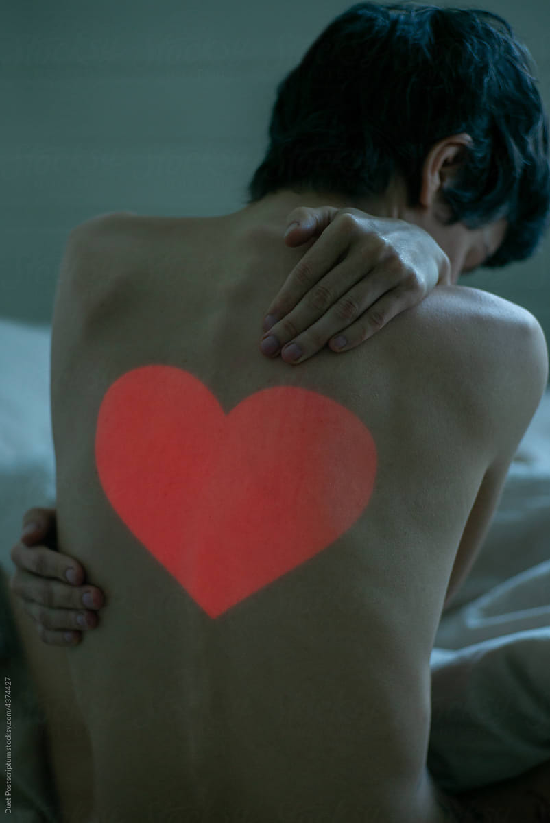 Woman in bed hugging herself with a heart on her back