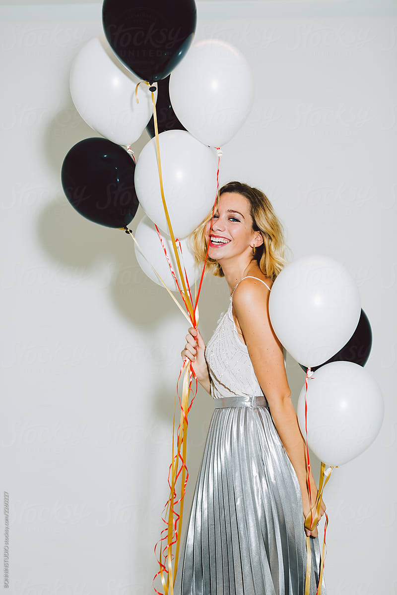 Smiling beautiful woman holding balloons in a New Year party celebration.