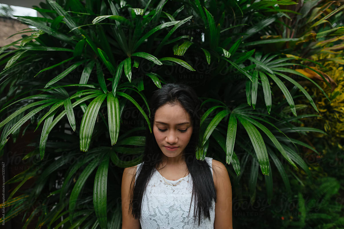 Young balinese woman looking down in bushes