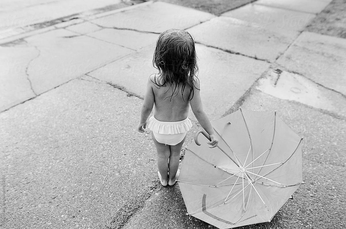child stands in rain with umbrella