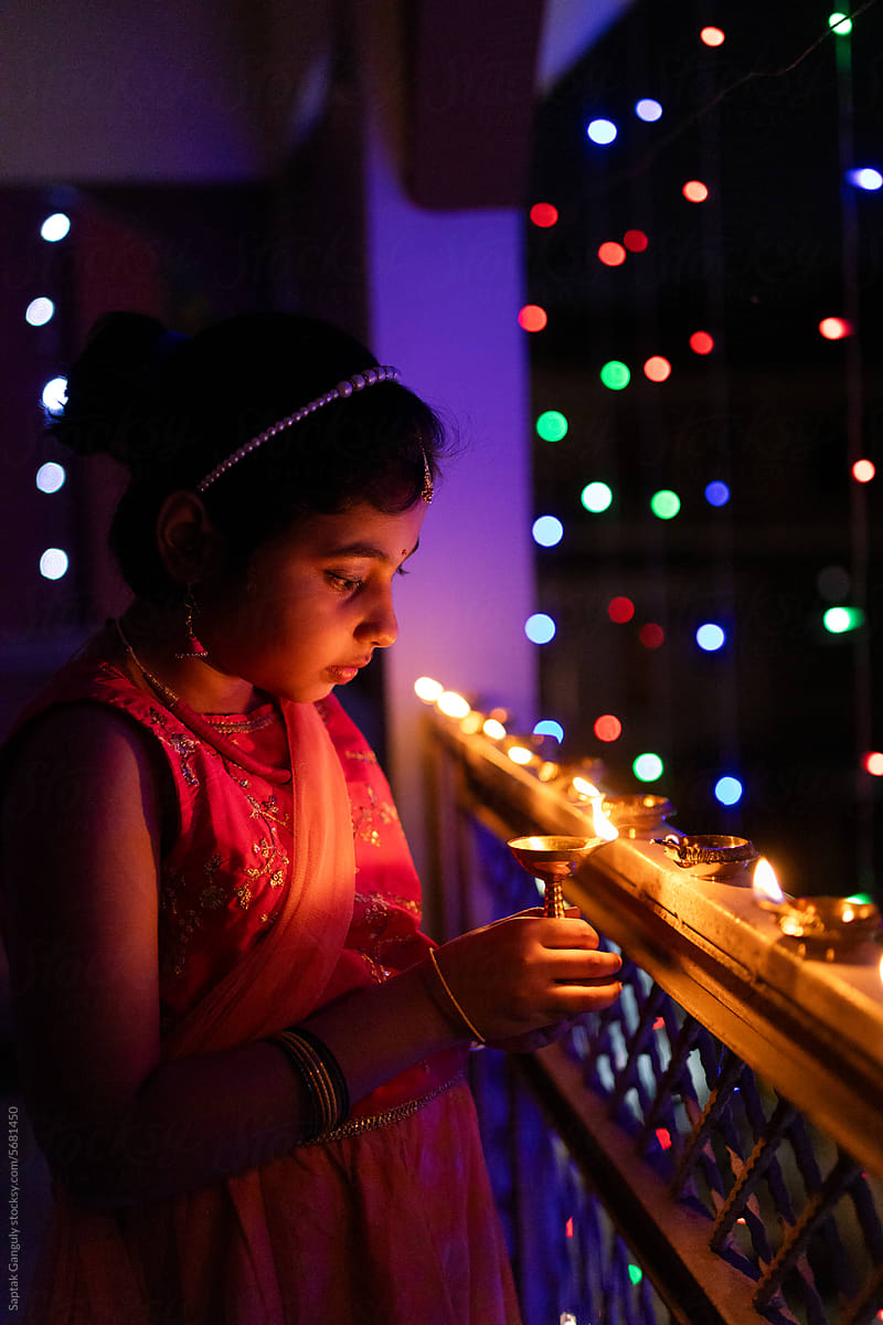 Little girl igniting oil lamps during diwali
