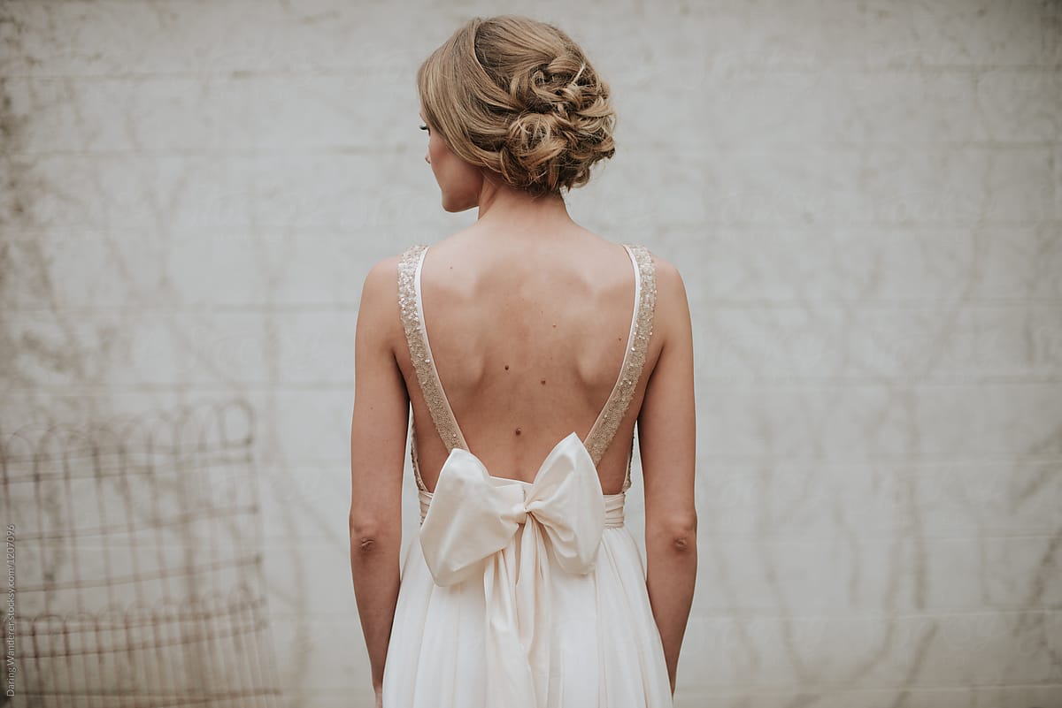 Delicate petite bride in simple minimalist wedding dress with large bow sash
