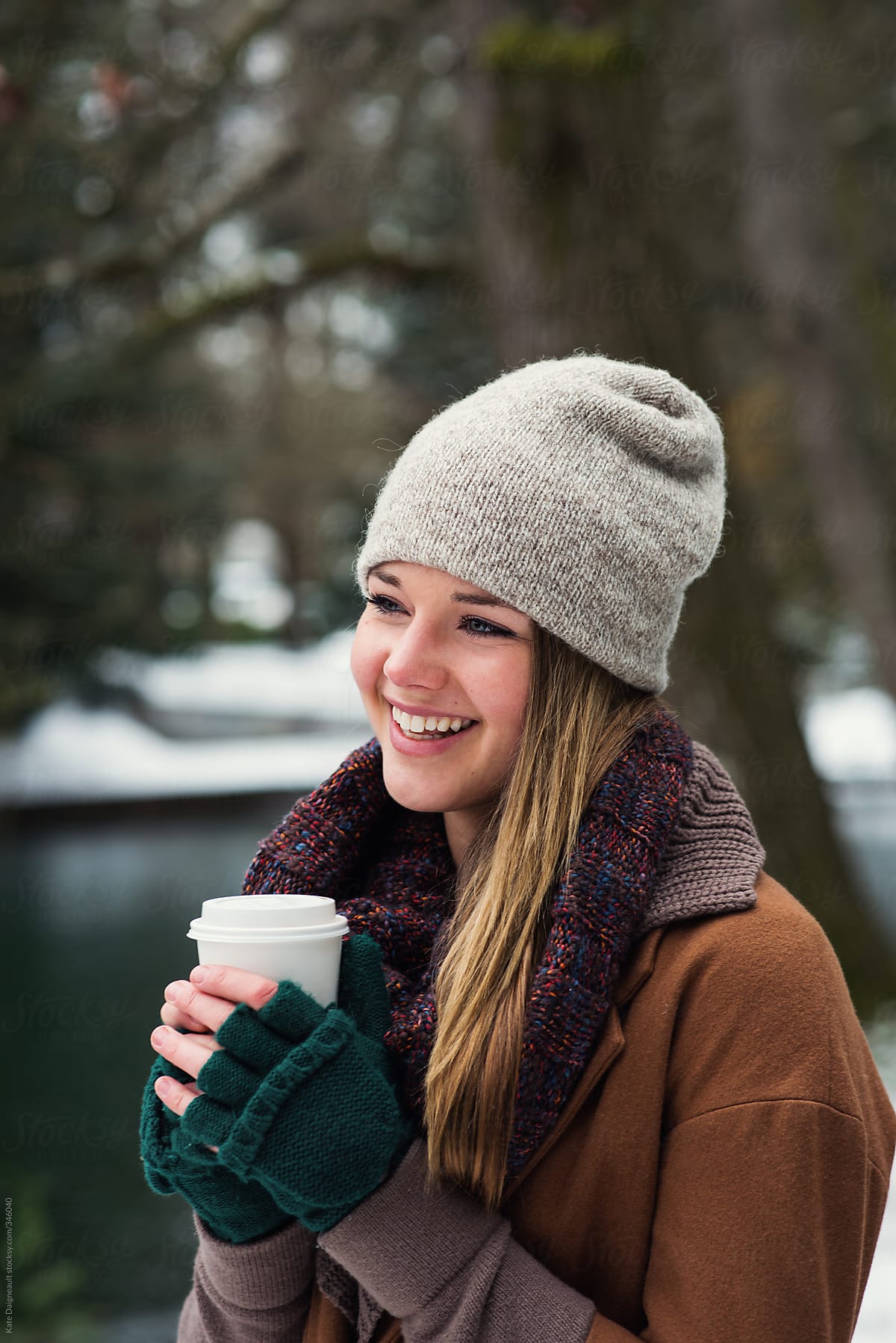 A young woman hold a hot beverage in the park in winter.